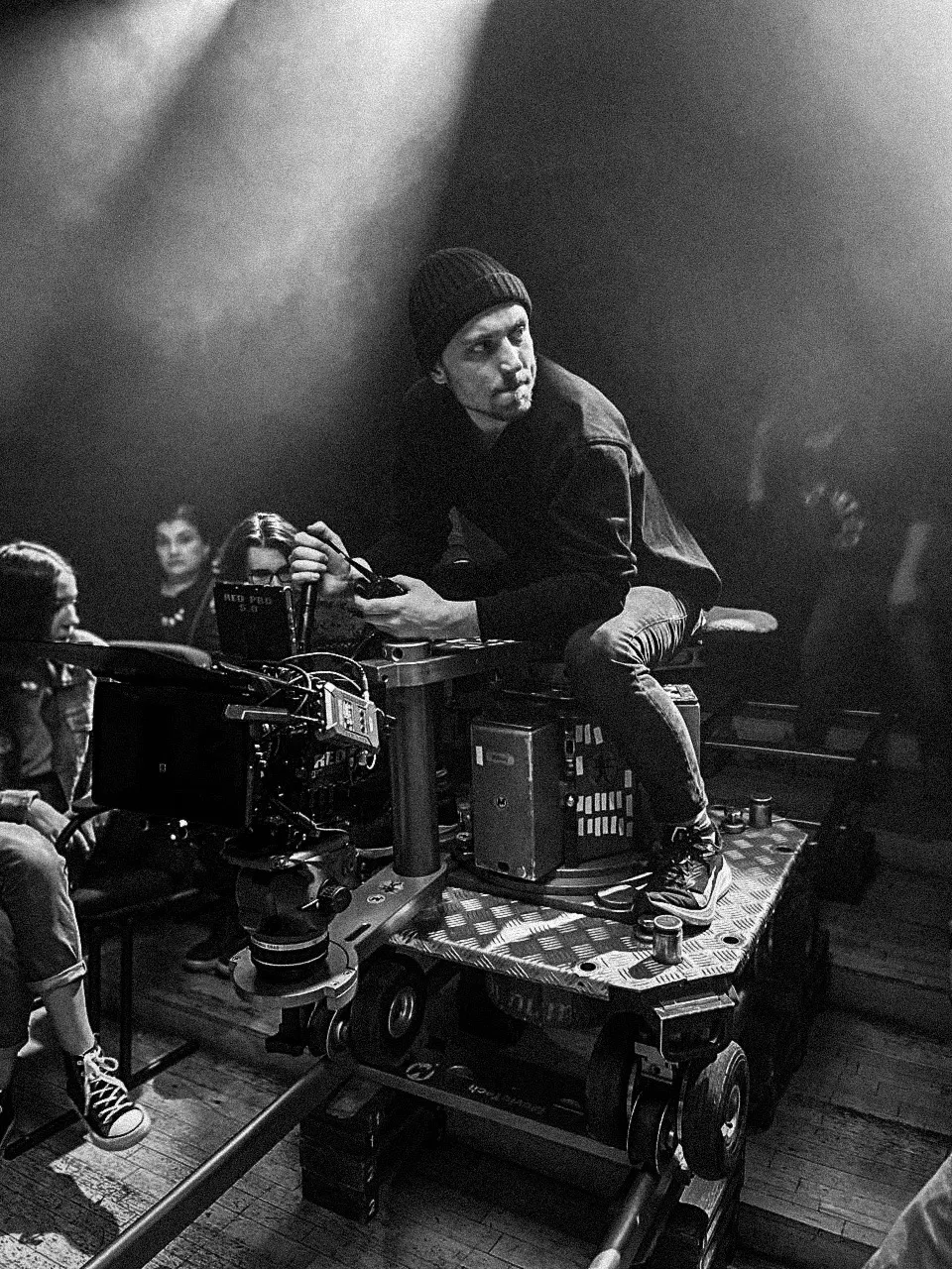 Max Golov seated beside a cinema camera on set